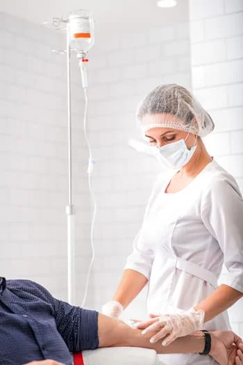 врач ставит пациенту капельницу